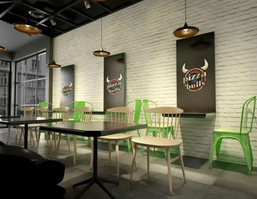 Helle Pizza & Burger Bulls Filiale mit weißer Backsteinwand und grünen Stühlen